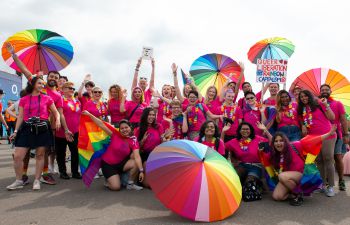 A group wearing University of Sussex-branded pink T-Shirts gathers at the start of Pride 2019