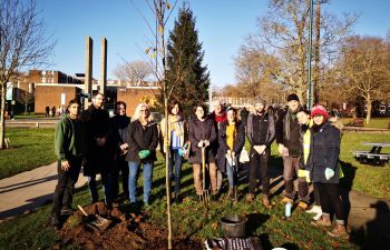 A Green Impact Team, dressed in outdoor wear and holding shovels, coming together for a tree planting activity on campus.