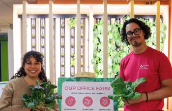 Two people smiling and holding crops from the farm