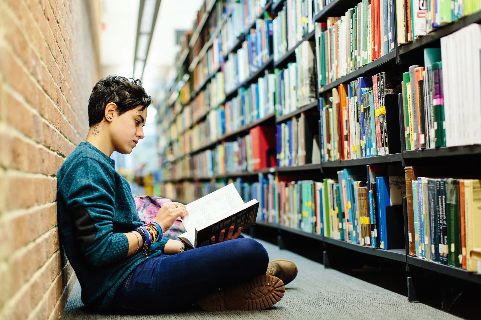 Student reading a book in the library at the University of Sussex