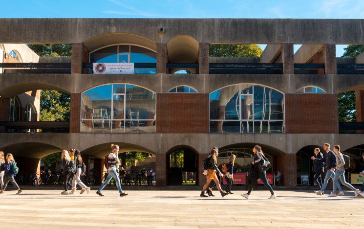 Campus building with students walking across square on sunny day